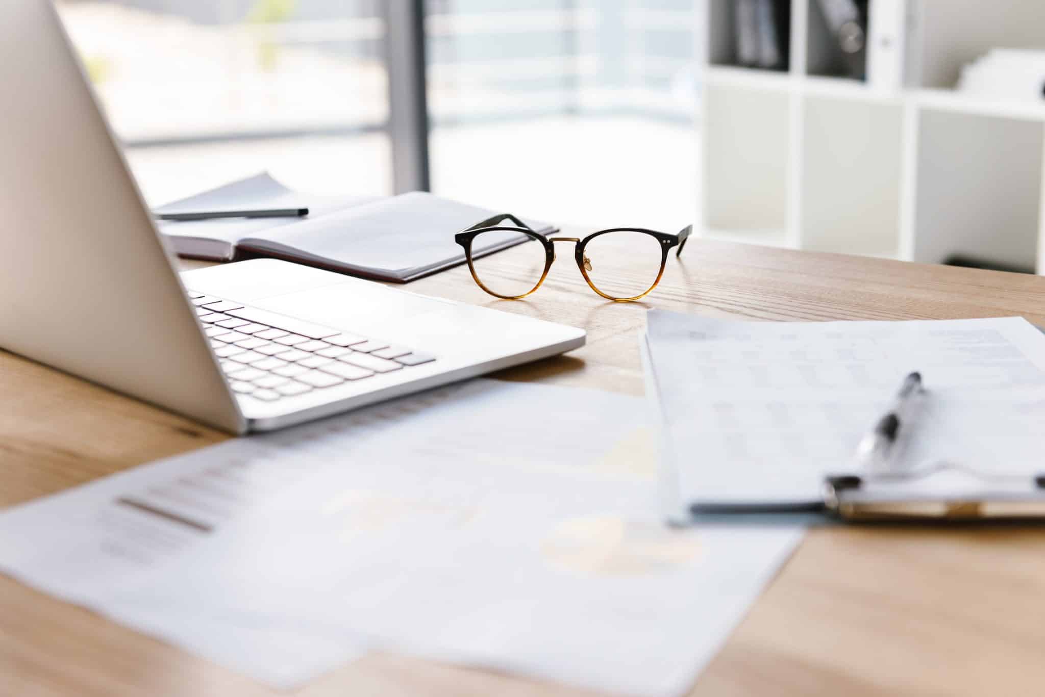 Image of workplace in office room without people with open laptop