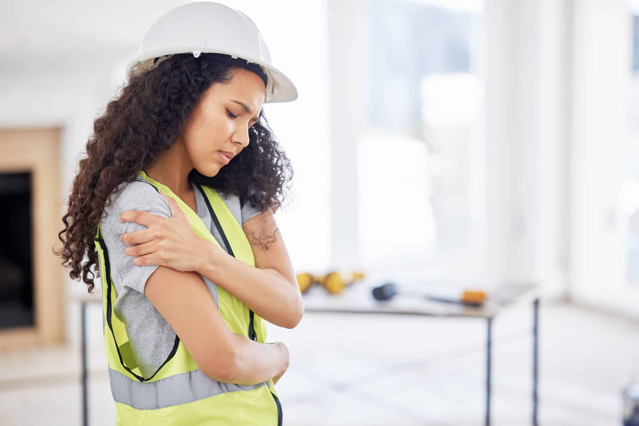 Shot of an attractive young contractor standing alone inside and suffering from a shoulder injury.